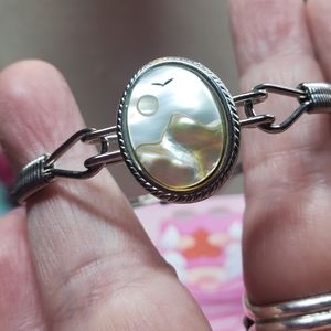 Silvertone bangle bracelet with a mother-of-pearl Inlay of a sun, bird & mountai